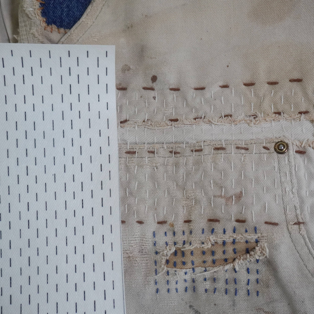 Close up of visible mending on a pair of pants next to a lined stick and stitch pattern.