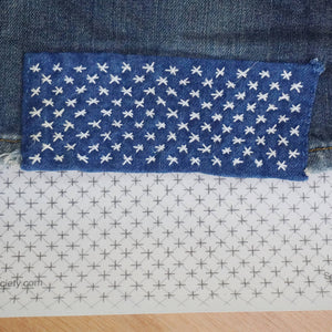Stitched up star pattern on the cuff of a pair of jeans with the stitck and stitch pattern in the background. 