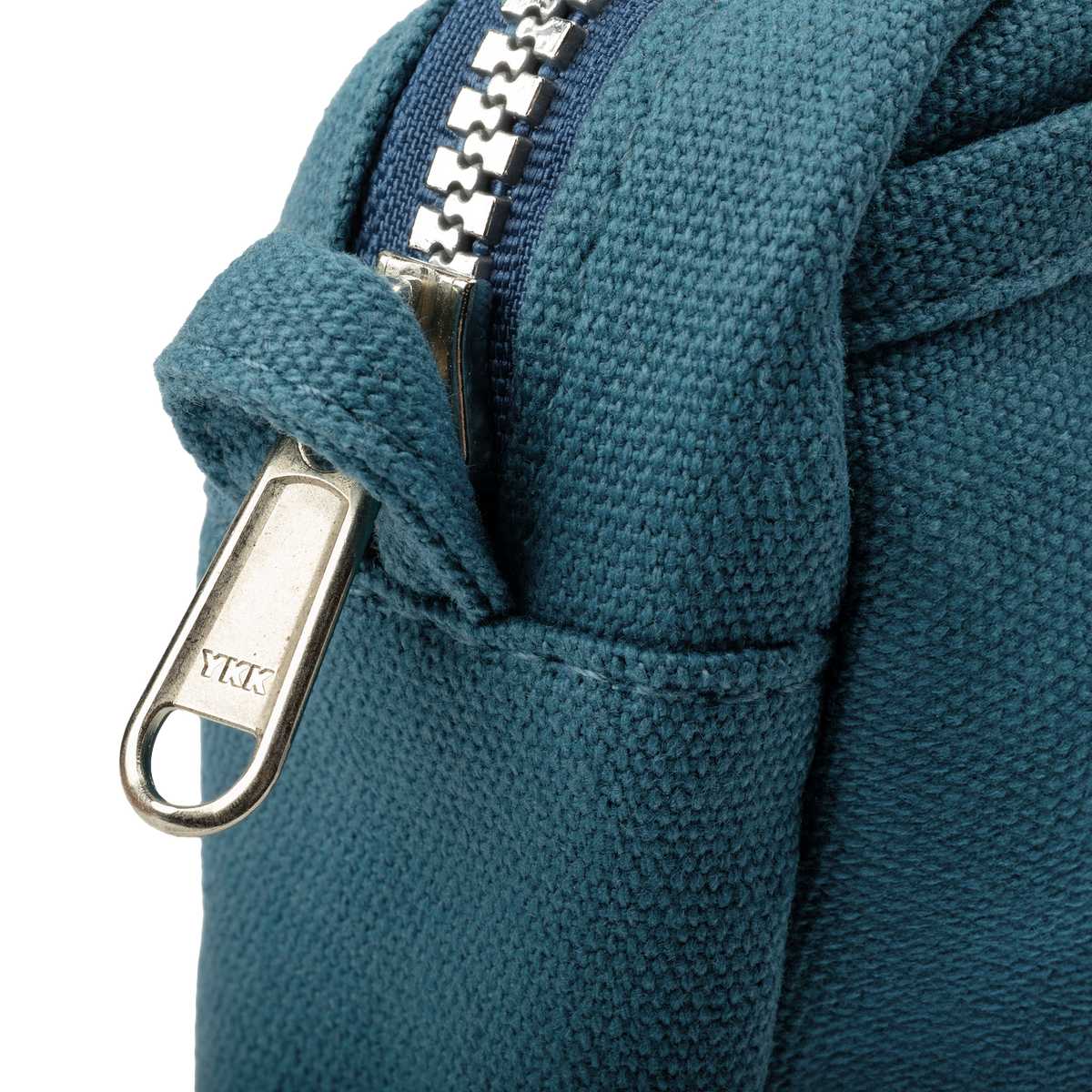 Close-up of a blue fabric bag with a metal zipper, featuring the YKK brand.