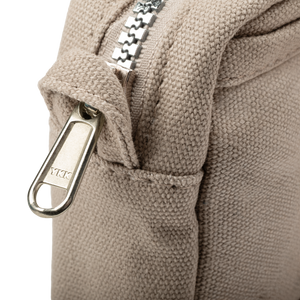Close-up of a beige textured bag with a silver zipper and YKK brand tag.