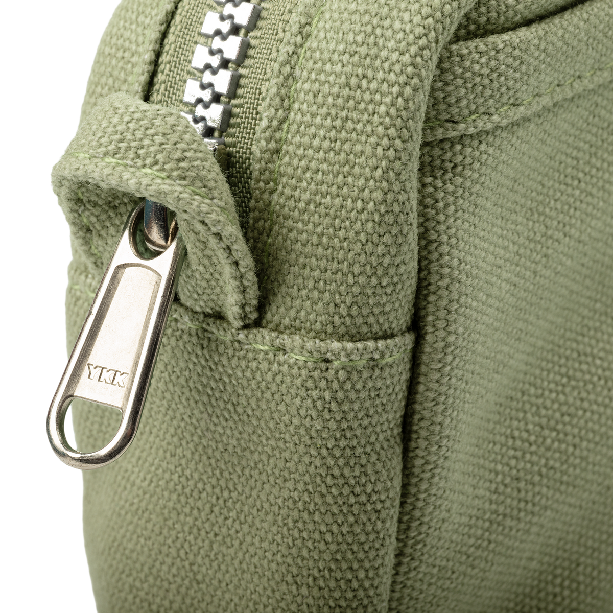 Close-up of a green fabric bag with a metal zipper and YKK branding.