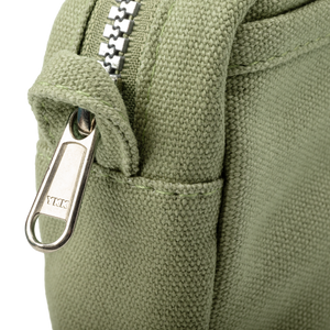 Close-up of a green fabric bag with a metal zipper and YKK branding.