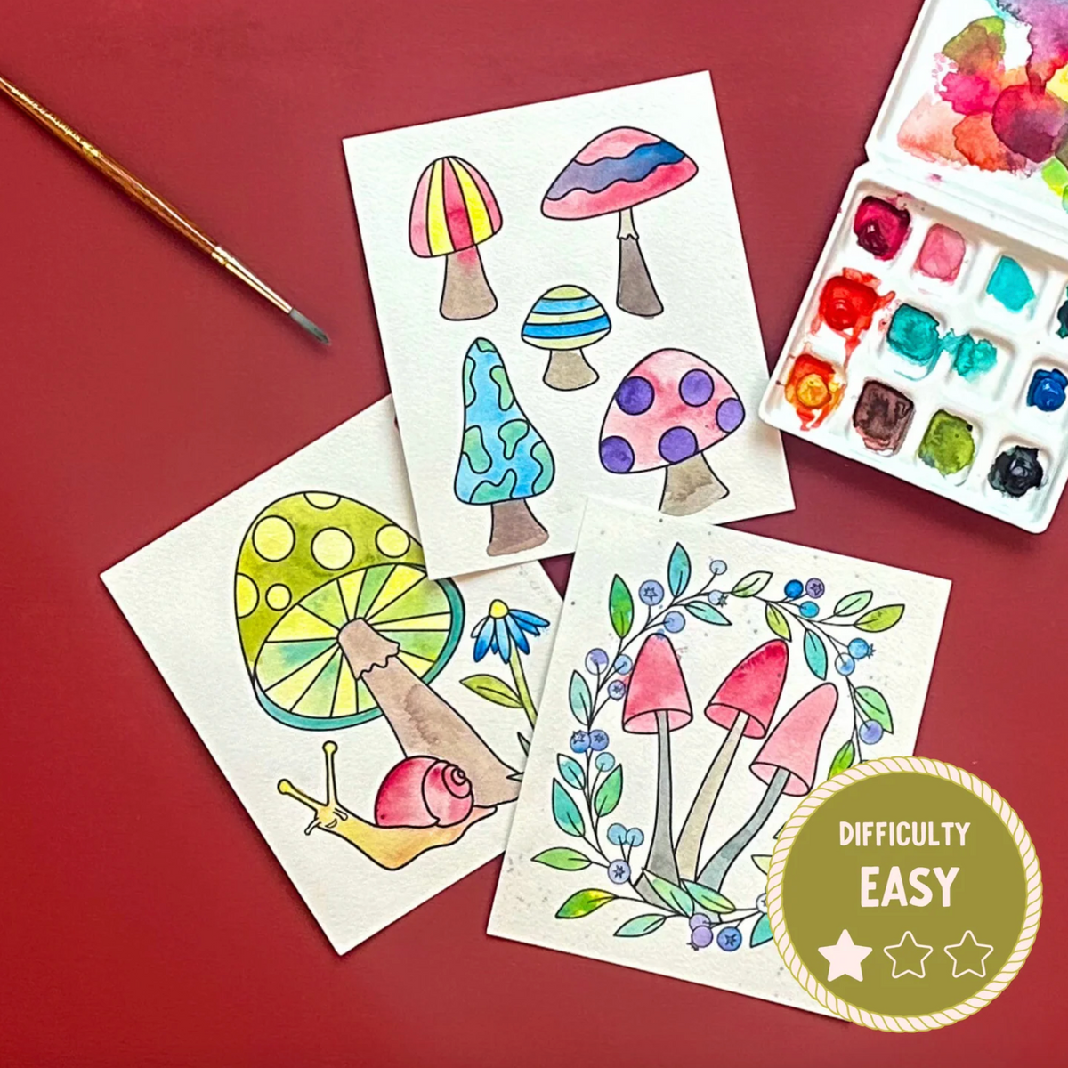 Coloring sheets with mushroom designs on a red background, accompanied by watercolors and a paintbrush.