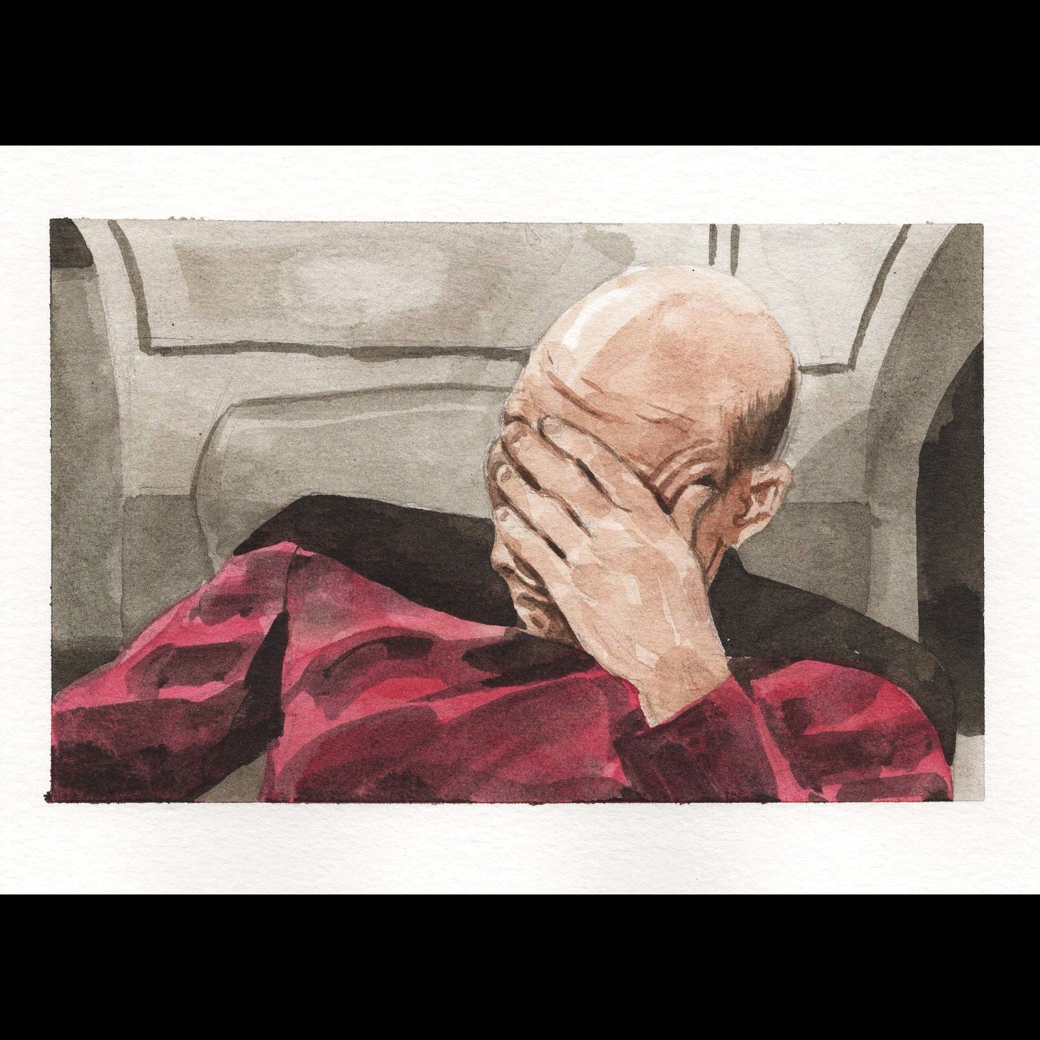 A bald man wearing a red shirt with his face in his hand against a gray background. 