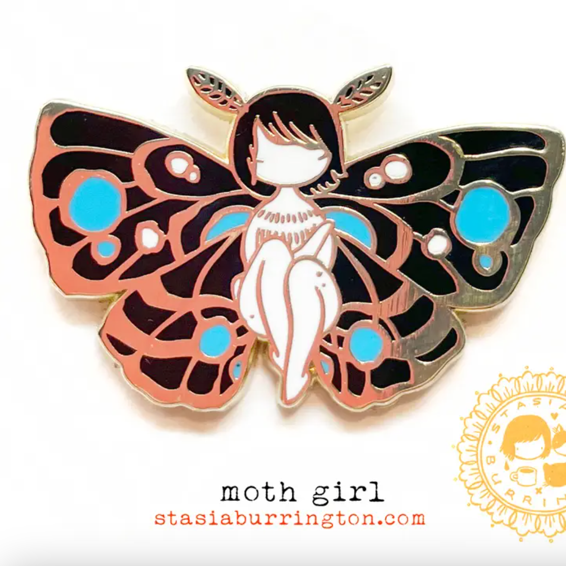 An enamel pin of a seated girl with blue and black moth wings and moth antennae