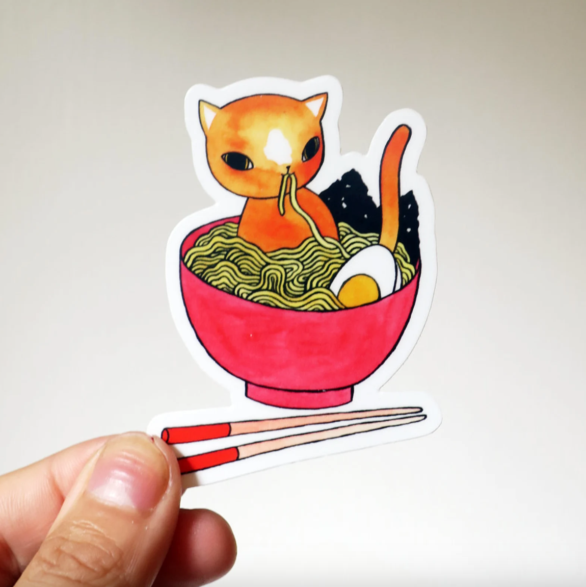 A sticker of an orange cat inside of a bowl of ramen.