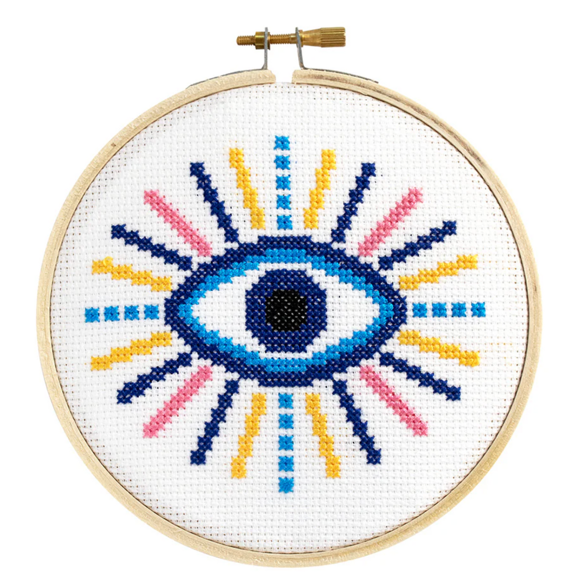 A cross stitch kit with a design of an evil eye in the center, featuring a combination of blue, pink, yellow, and black threads on a white aida cloth framed in a embroidery hoop.
