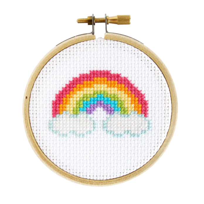 A completed mini cross stitch project depicting a rainbow, mounted in a 3 inch embroidery hoop.