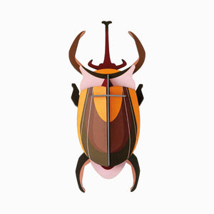 Cardboard sculpture of an elephant beetle against a white background. 