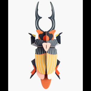 Cardboard sculpture of a giant stag beetle against a white background. 