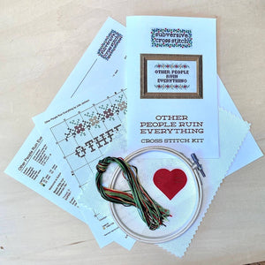 Cross stitch kit with pattern, hoop, and thread on a wooden surface