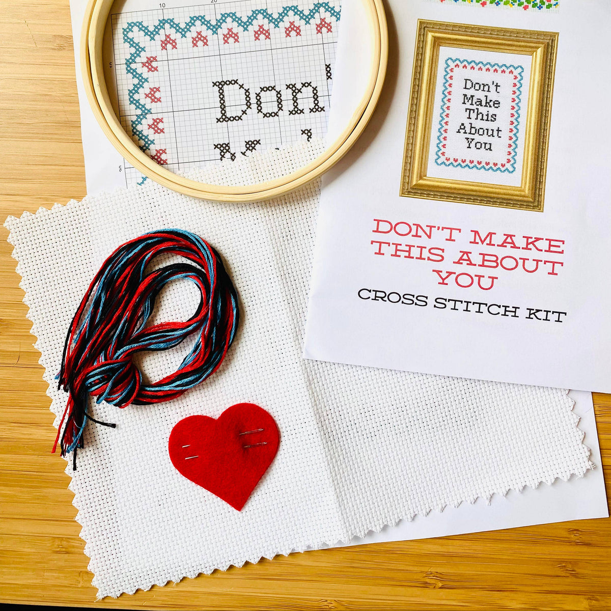 Cross stitch kit with hoop, thread, and printed pattern on a wooden surface