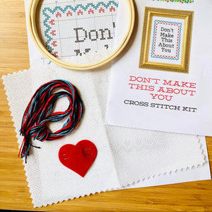 Cross stitch kit with hoop, thread, and printed pattern on a wooden surface