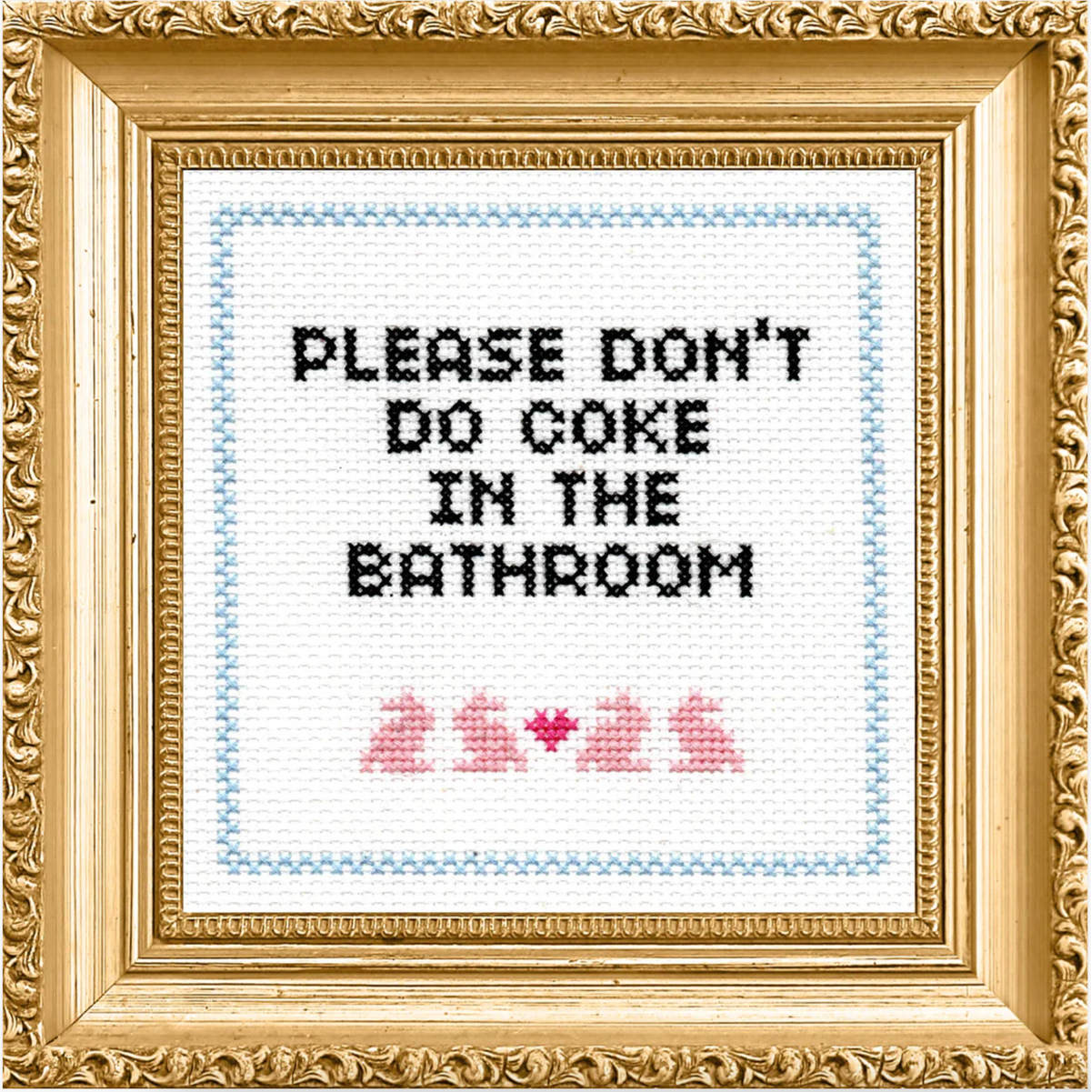 A finished cross stitch in an ornate gold frame that says "please don't do coke in the bathroom" with four pink bunnies and a heart 