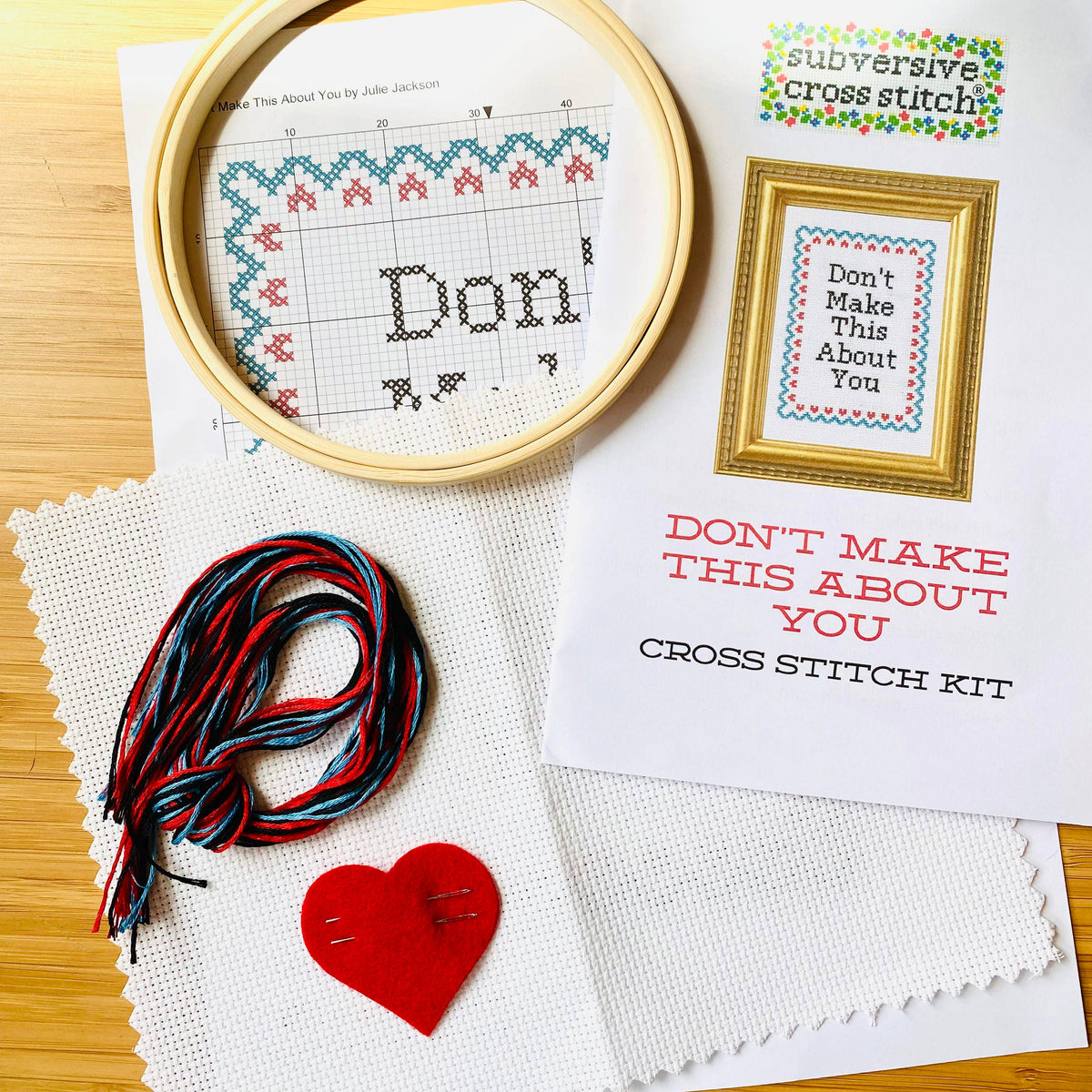 Cross stitch kit with hoop, thread, and printed pattern on a wooden surface