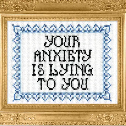 Decorative cross-stitch with 'Your anxiety is lying to you' text in a gold frame.