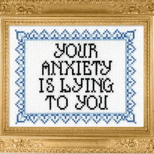 Decorative cross-stitch with 'Your anxiety is lying to you' text in a gold frame.