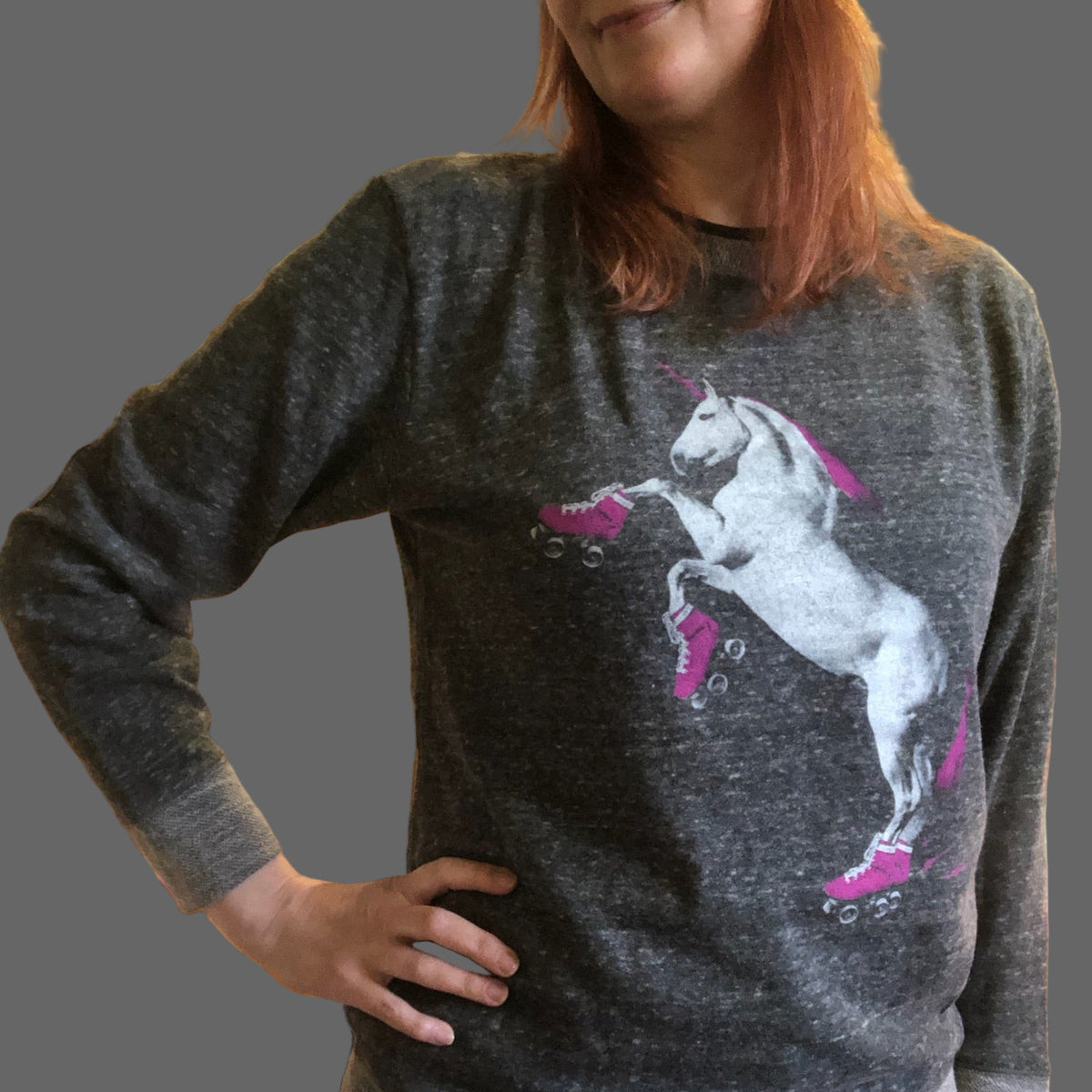 Person wearing a gray sweater with a roller skating unicorn graphic in a store setting. 