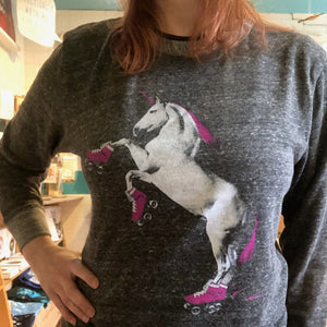 Person wearing a gray sweatshirt with a roller skating unicorn graphic design.