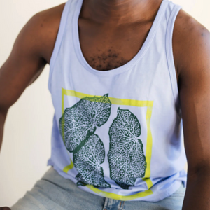 Man wearing a white tank top with green designs and a green hat against a plain background