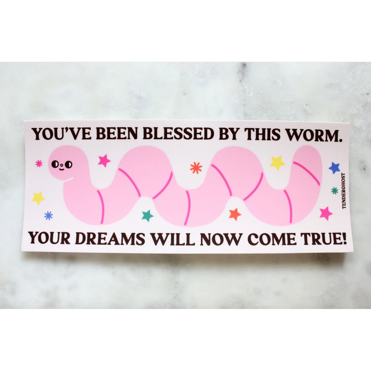 Pink cartoon worm bumper sticker with text that says "you've been blessed by this worm. your dreams will now come true!" on a marble background