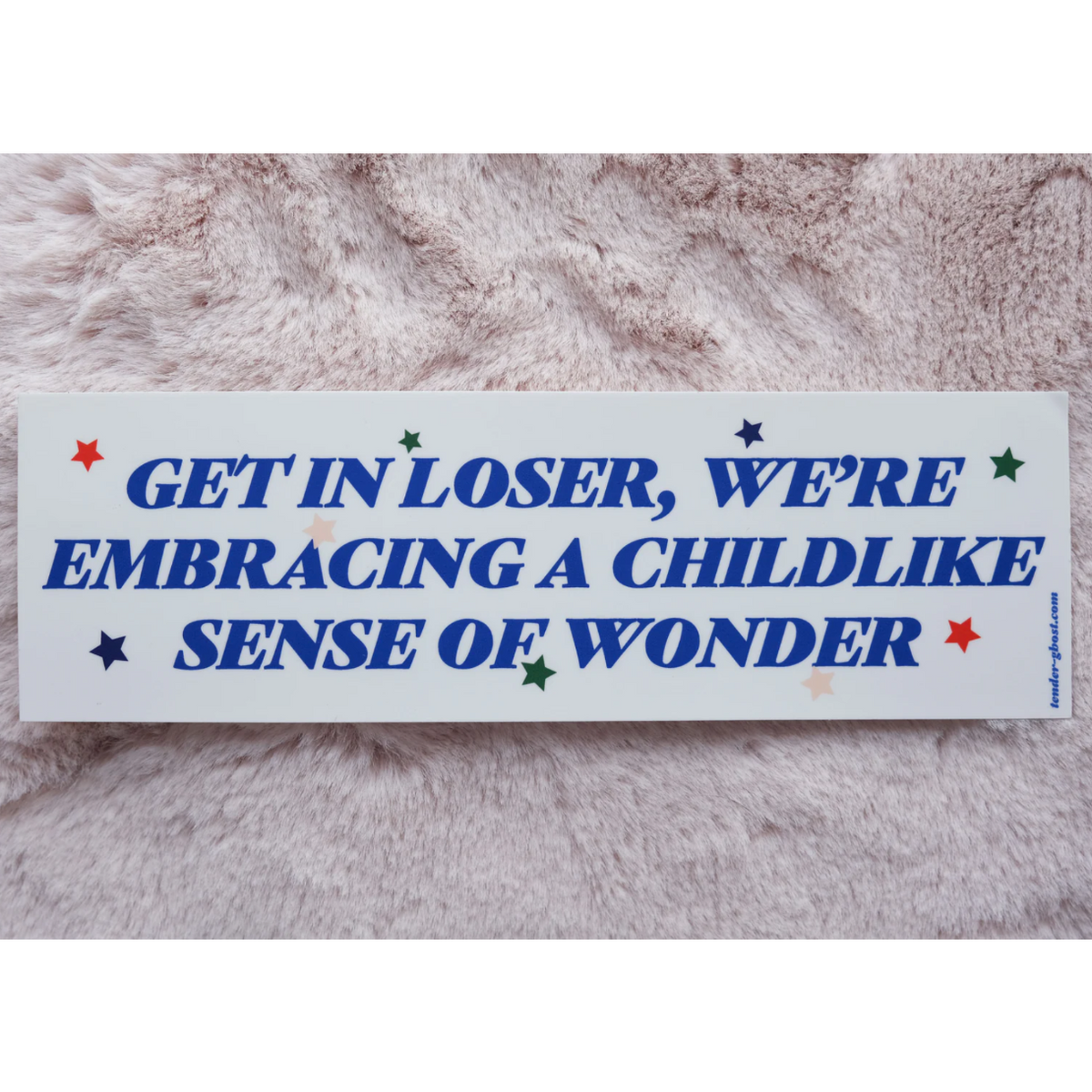 Sticker with text 'GET IN LOSER, WE'RE EMBRACING A CHILDLIKE SENSE OF WONDER' on a textured surface