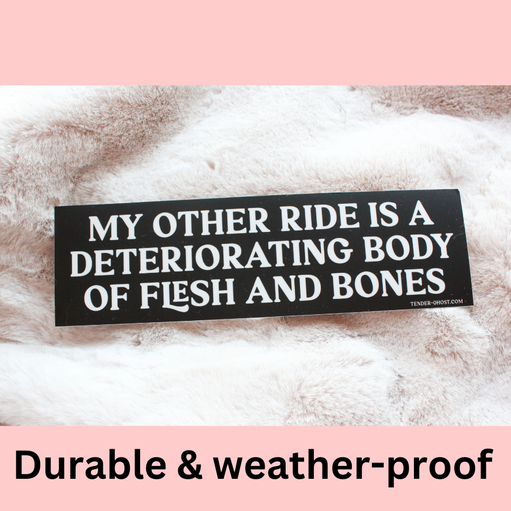 Black bumper sticker with white text that reads "My other ride is a deteriorating body of flesh and bones" against a fuzzy background 