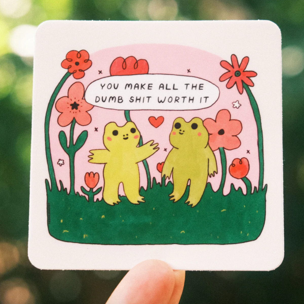 Cartoon illustration of two frogs and flowers with a text that says "you make all the dumb shit worth it" on a white background.