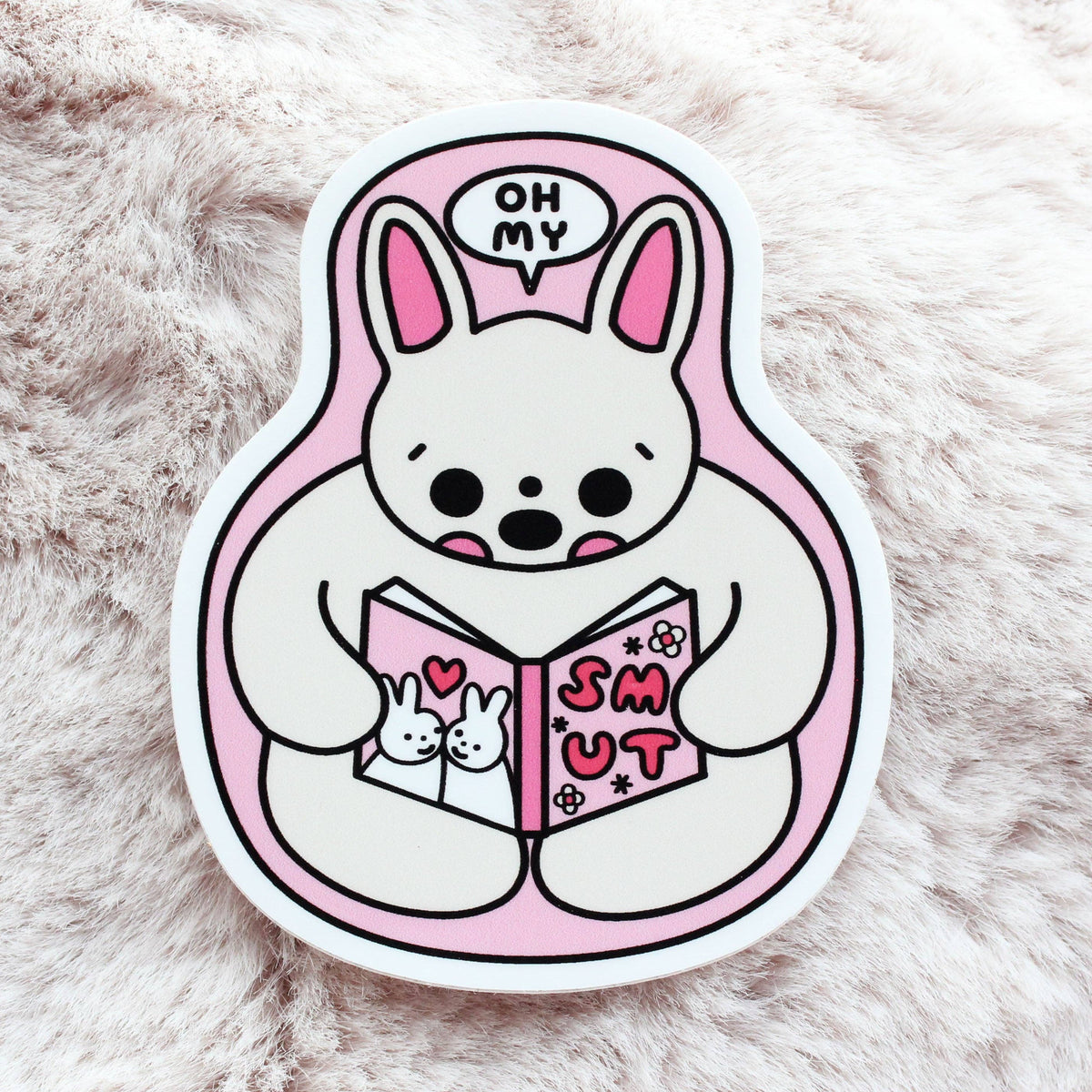 Cartoon character sticker reading a book with a pink background on a fluffy white surface
