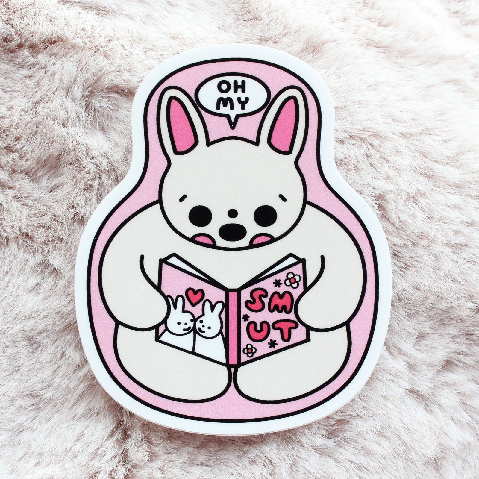 Cartoon character sticker reading a book with a pink background on a fluffy white surface