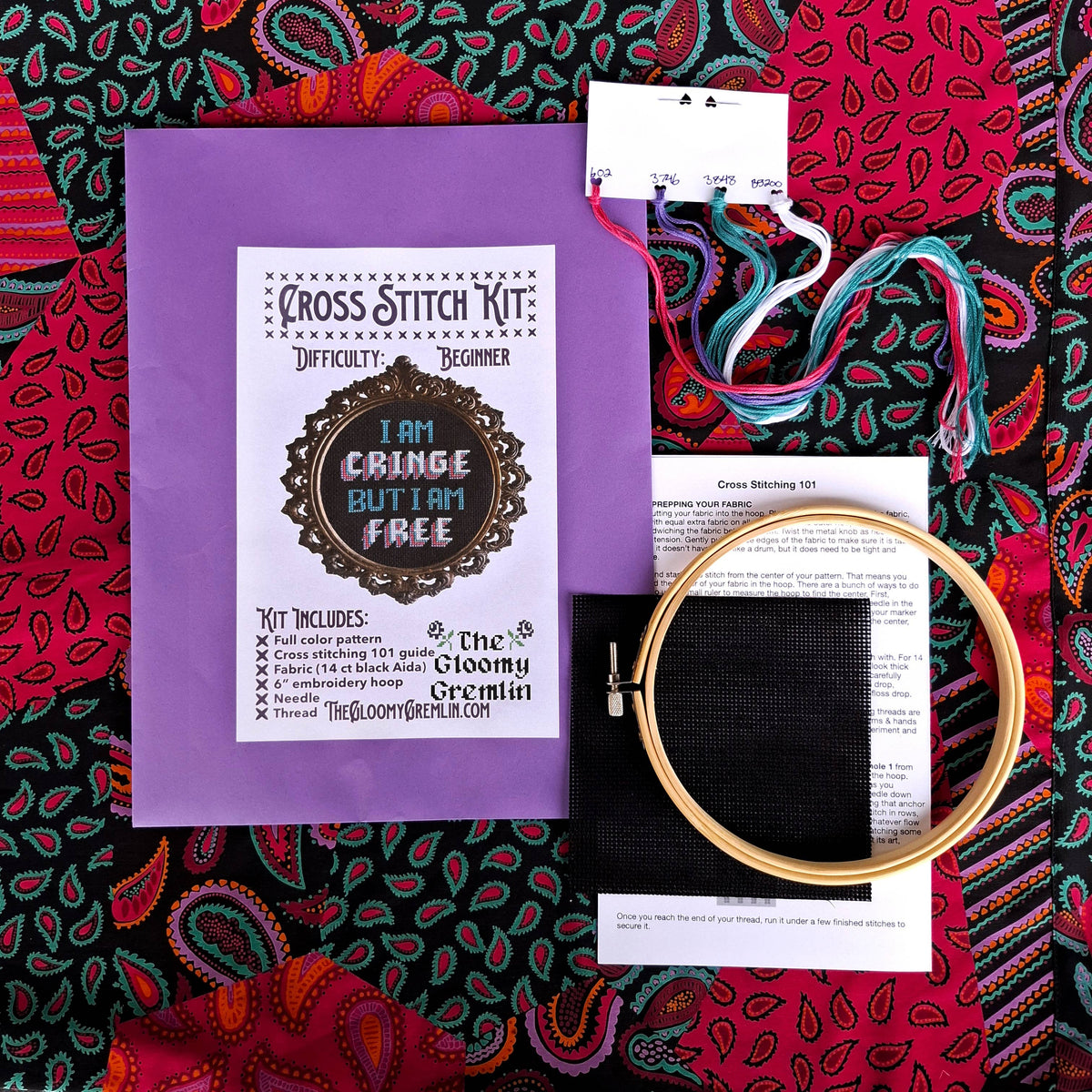 Cross stitch kit with hoop and thread on a colorful patterned fabric background