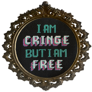 Decorative frame with cross-stitched text 'I AM CRINGE BUT I AM FREE' on a white background