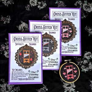 Cross stitch kit with a completed design on a dark floral background