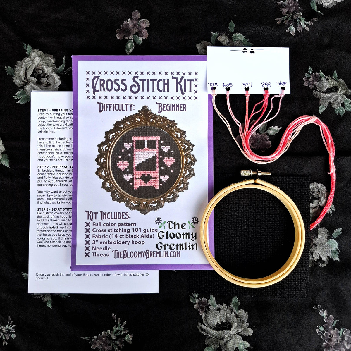 Cross stitch kit with embroidery hoop, thread, and pattern on a dark background