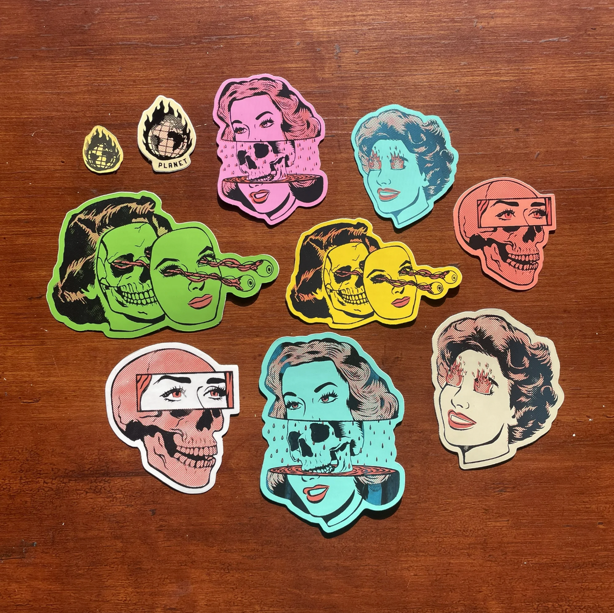 10 stickers of varying sizes and colors depicting cartoon women with fire in their eyes, skulls, and eyeballs shooting out of their heads. 