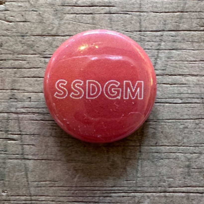 Red button with 'SSDGM' text on a wooden surface