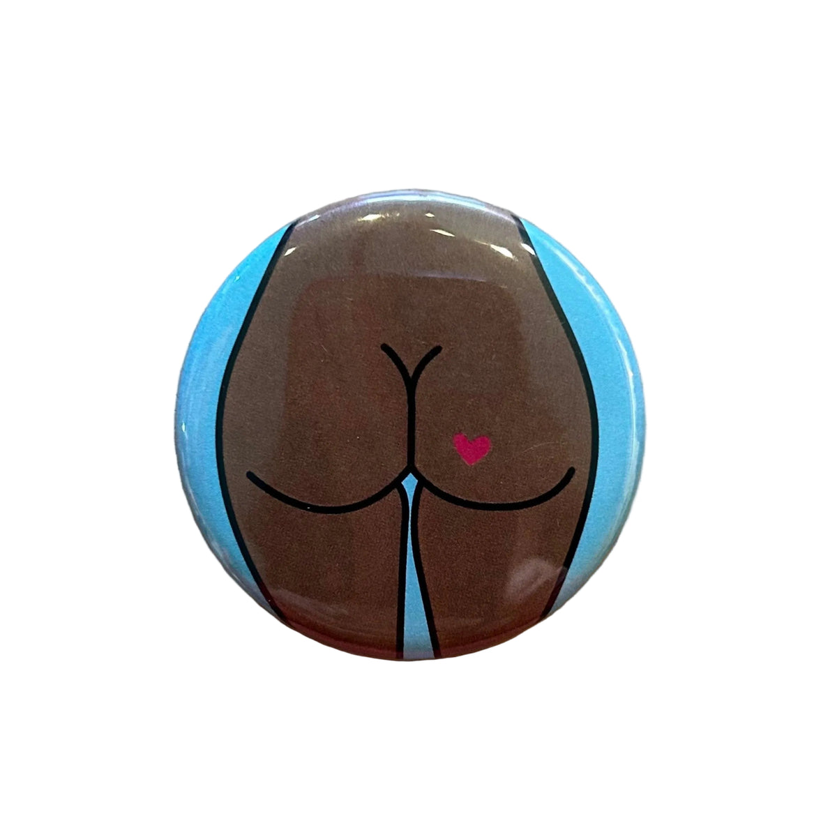 Round button featuring a design of a butt with a heart tattoo against a light blue background. 