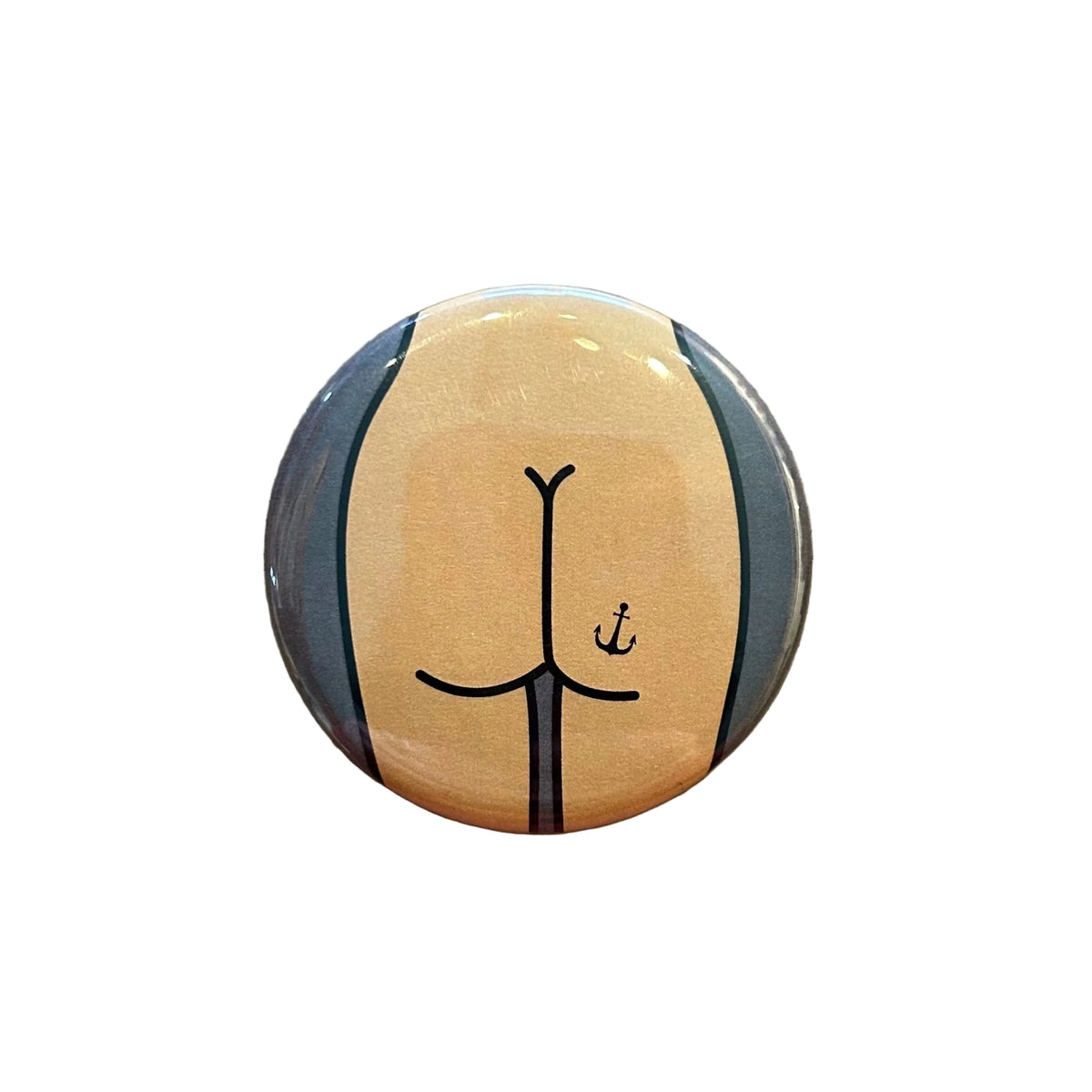 Round pin featuring a drawing of a butt with an anchor tattoo on a dark gray background. 