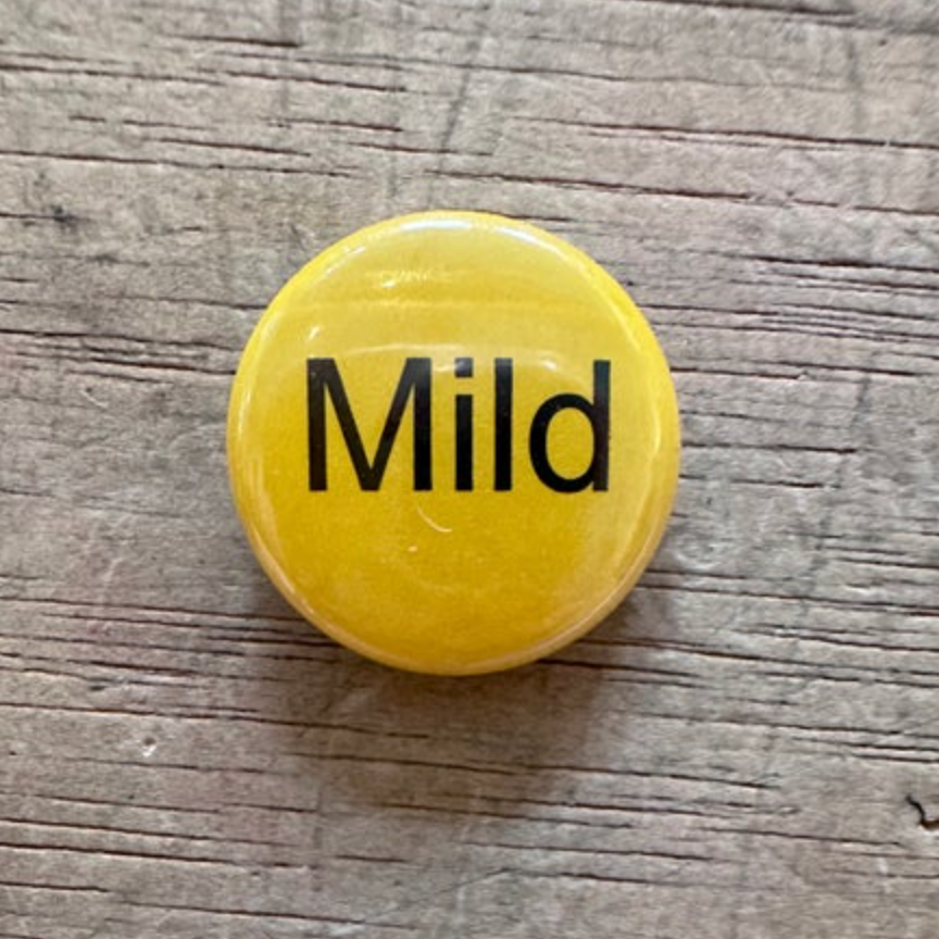 Yellow button with 'Mild' text on a wooden surface