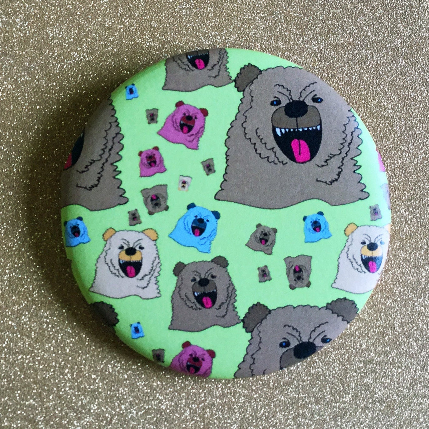 Round green magnet with a repeating pattern of cartoon growling bears on top of a glittery gold backdrop. 