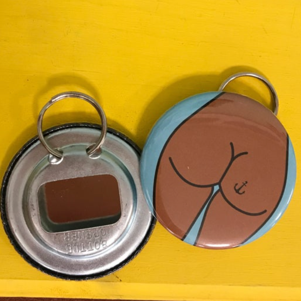 The front and back of a bottle opener keychain, featuring a design of a brown butt with an anchor tattoo, against a bright yellow background. 