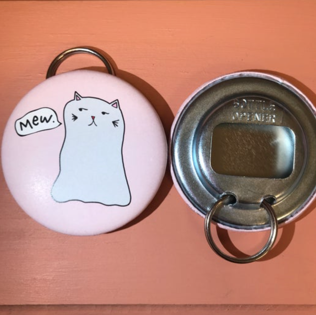 Pink bottle opener with a cat illustration on a wooden surface