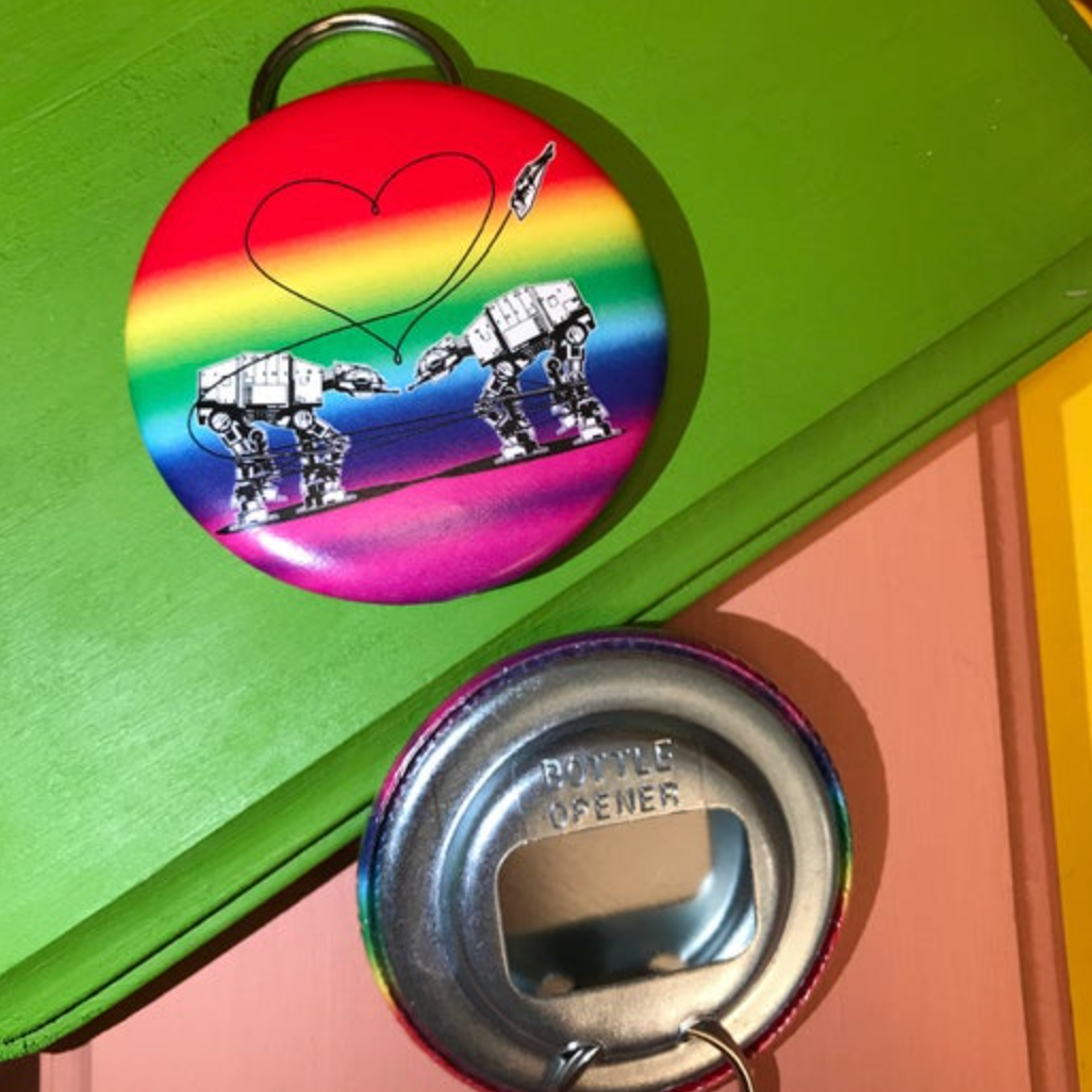 Rainbow bottle opener with the Love AT-AT First Sight design against a green and peach background. 
