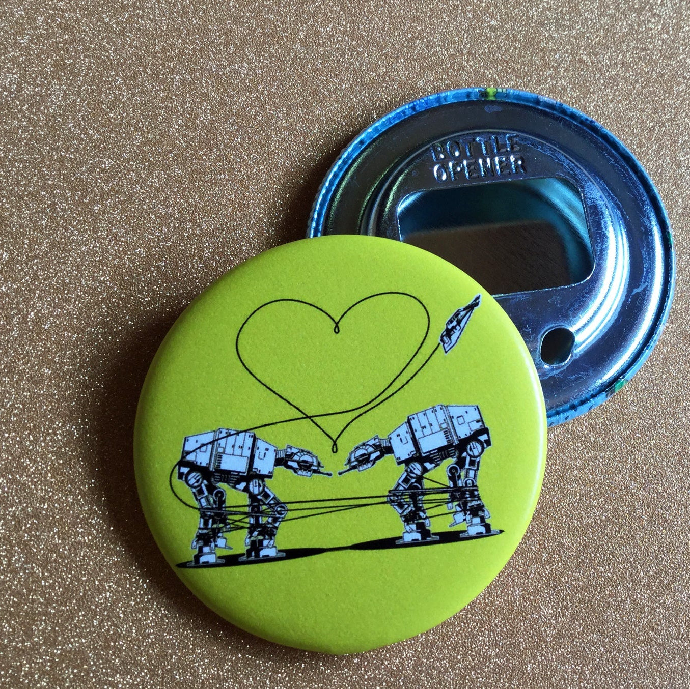 Yellow bottle opener with robot design and heart on a gold glittery surface