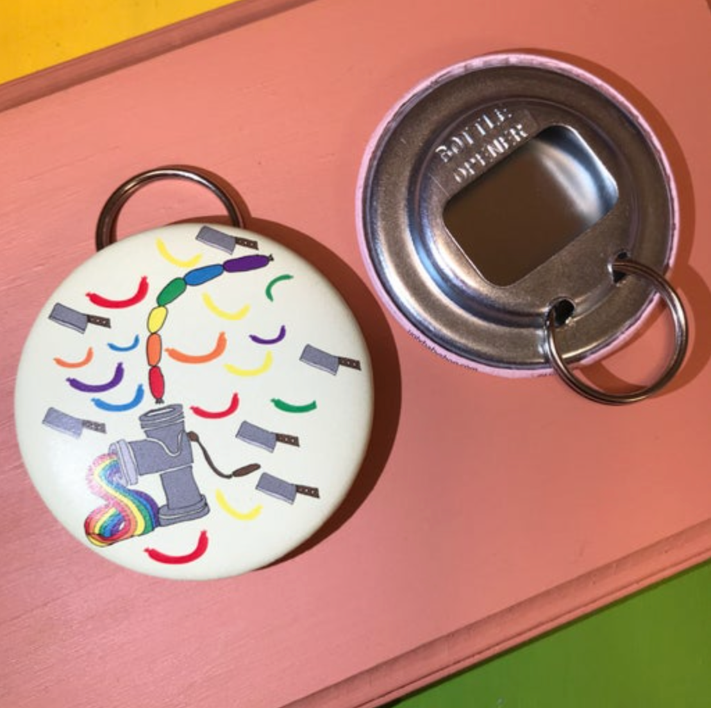 Round bottle opener keychain featuring a design of cleavers and a sausage machine making rainbow sausages against a peach background. 