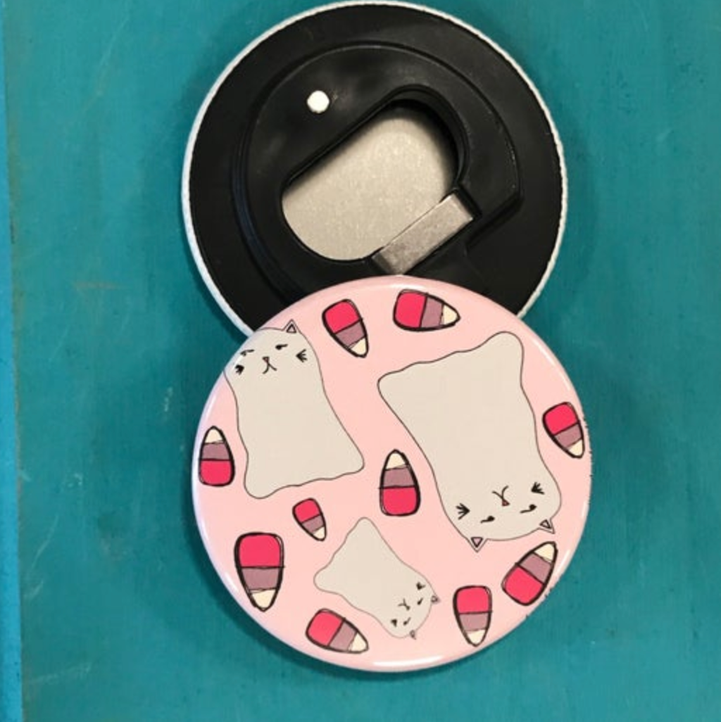 Bottle opener with cat design on a pink background against a teal background