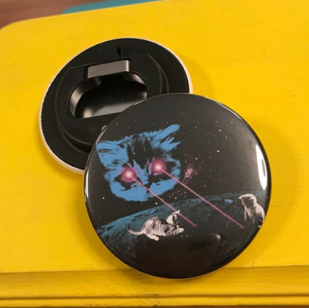 Round bottle opener magnet featuring a cat with laser eyes pointing at two kittens. 