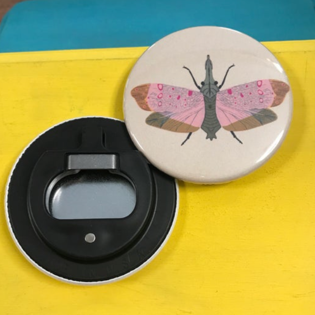 Bottle opener with moth design on a yellow surface