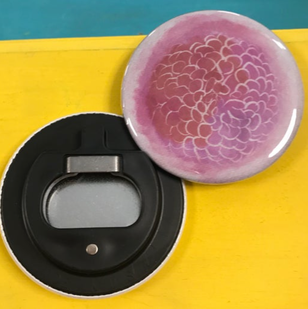 Black bottle opener with pink floral design on a yellow surface