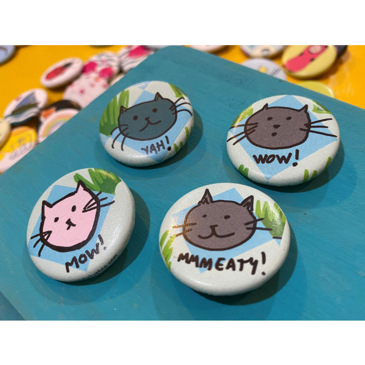 Four cat-themed buttons with different expressions and text on a blue surface.